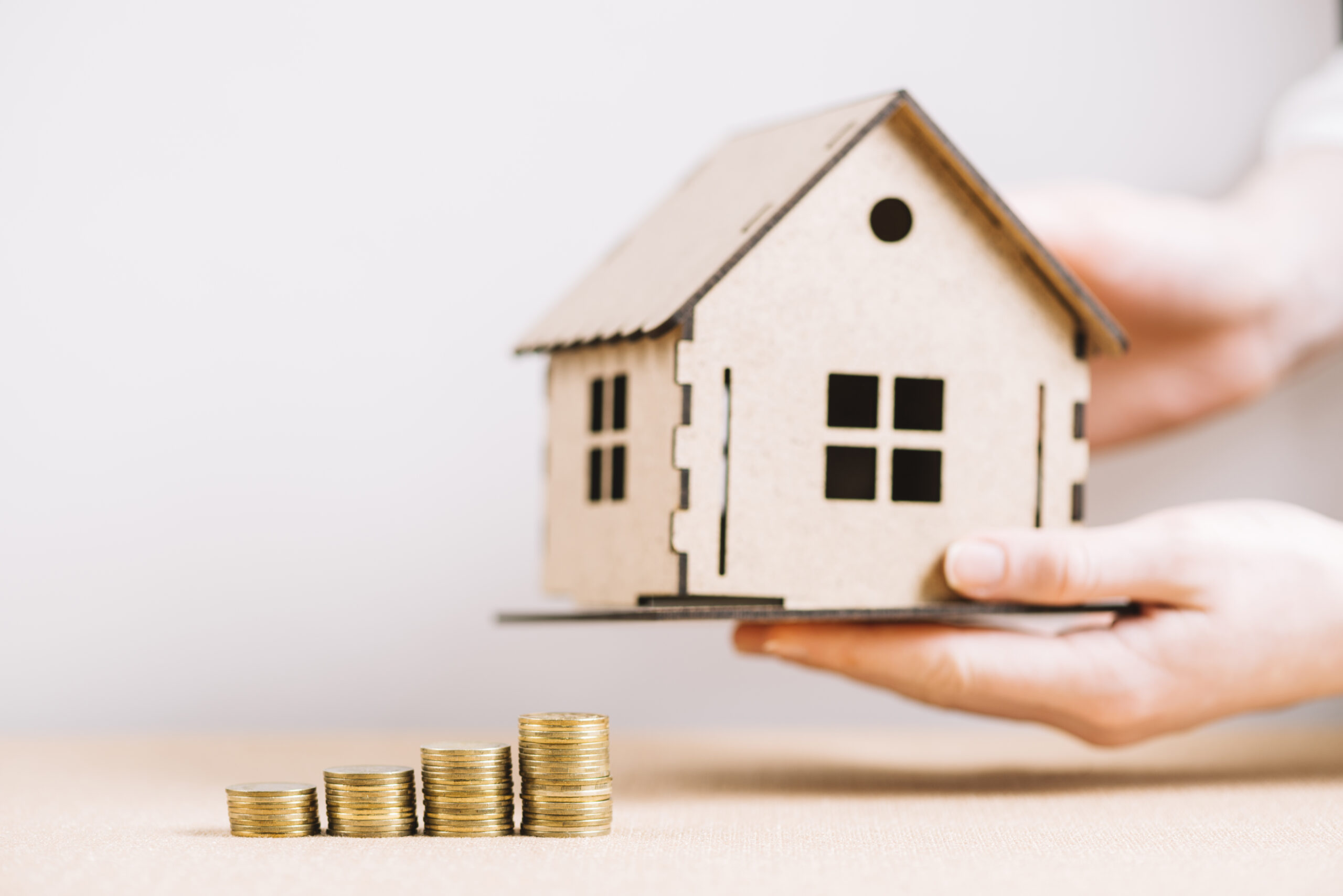 crop-hand-holding-house-near-coins